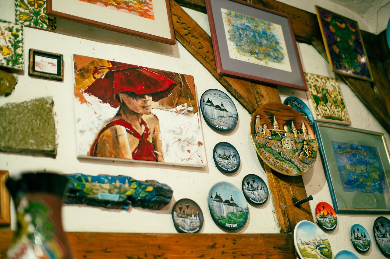 A collection of colorful paintings and decorative plates displayed creatively on a wooden wall.